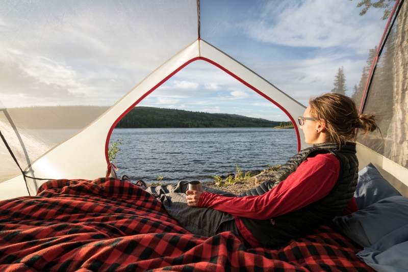 Woman camping and drinking coffee in a tent
